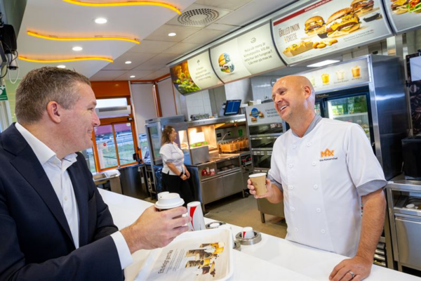 En person köper kaffe av en person bakom kassan på MAX