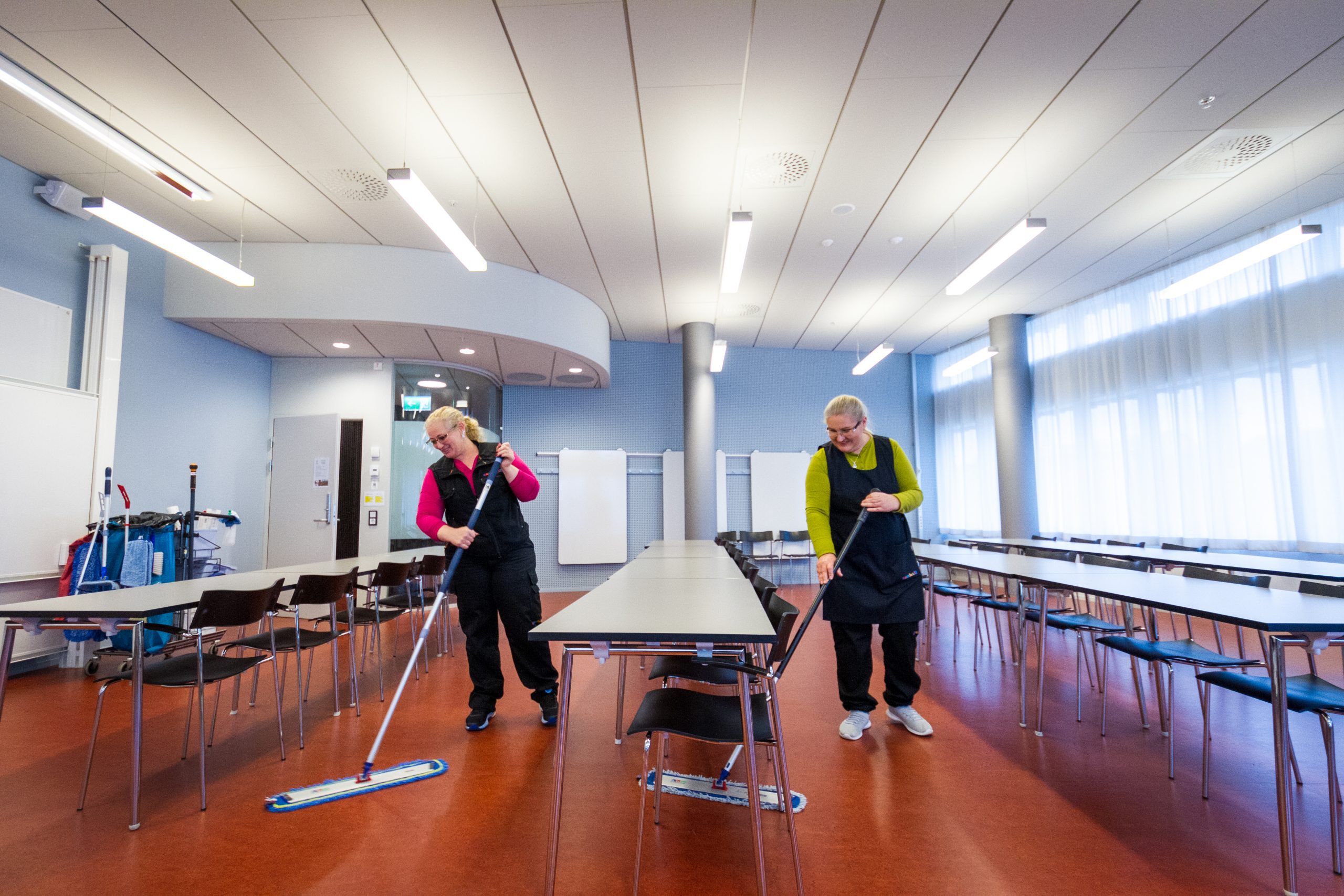 Två personer städar konferenslokal