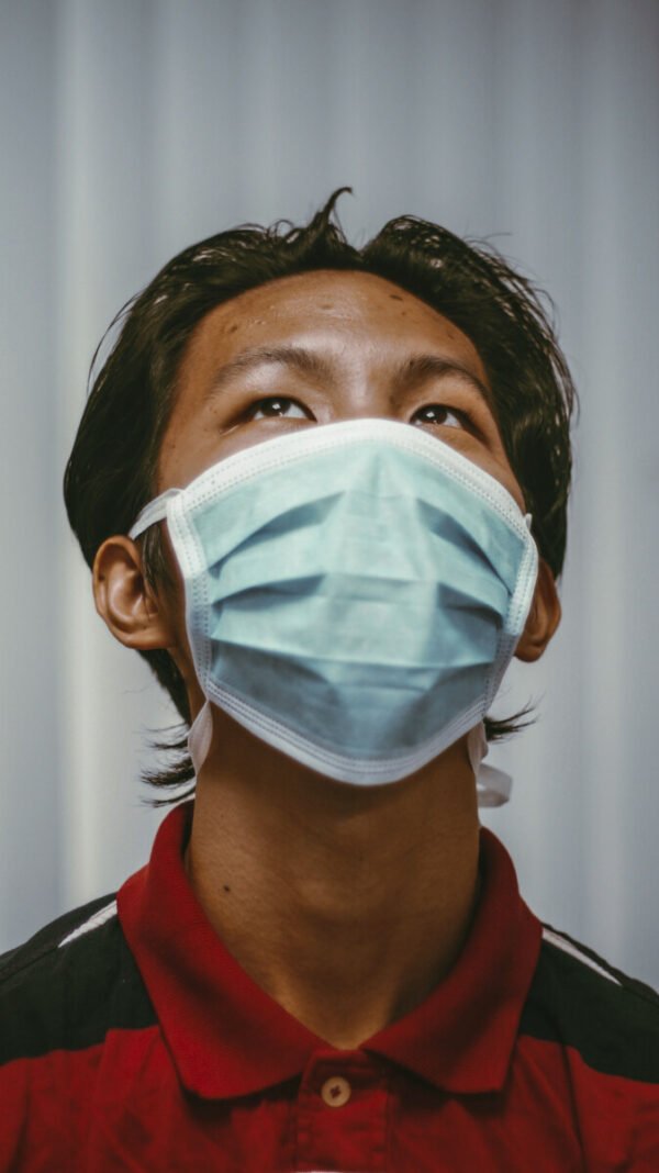 Man med mörkt hår, röd tröja och munskydd kollar upp mot taket