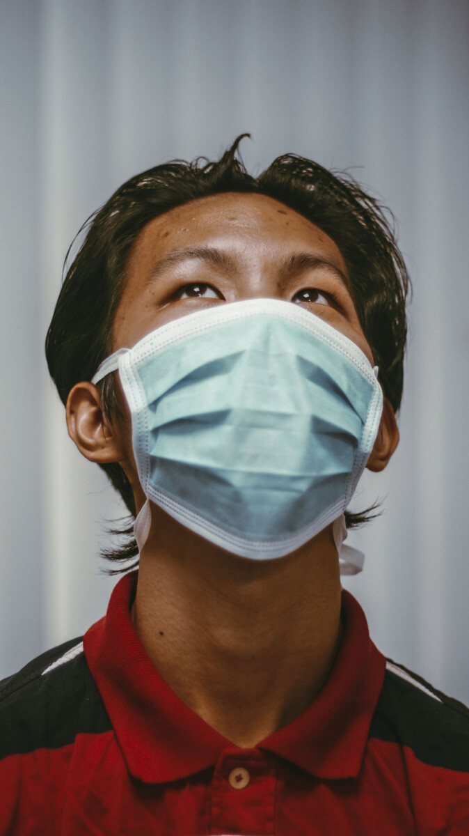 Man med mörkt hår, röd tröja och munskydd kollar upp mot taket