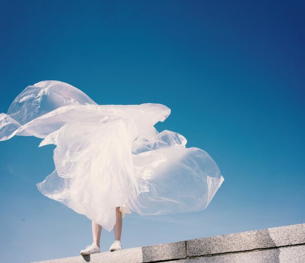 Person står på mur men man ser bara benen för resten är täckt i plast som flyger runt