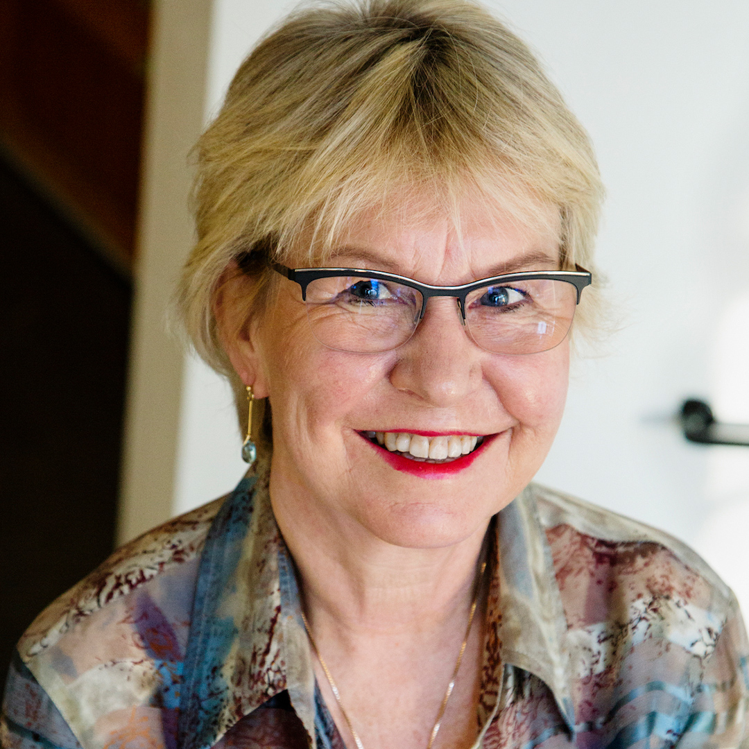 Kvinna med kort blont hår, glasögon och rött läppstift