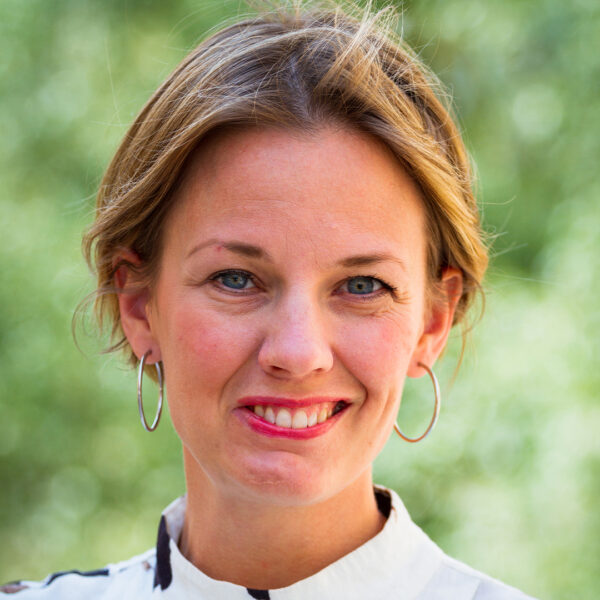 bild på Anna Hagvall som ler och tittar in kameran. Grön bakgrund.