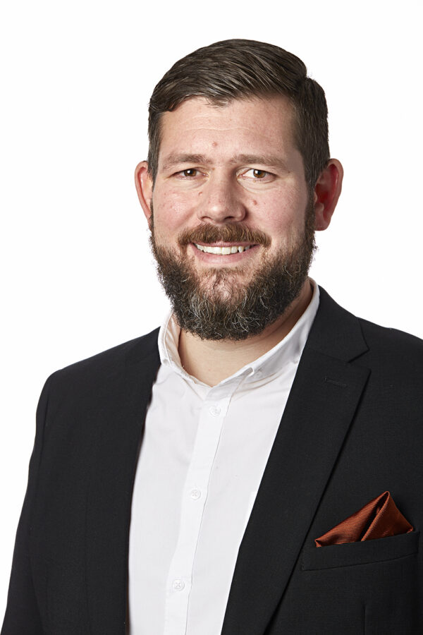 Porträtt av Erik Olsson Wahman. Han bär vit skjorta och svart kostym. 