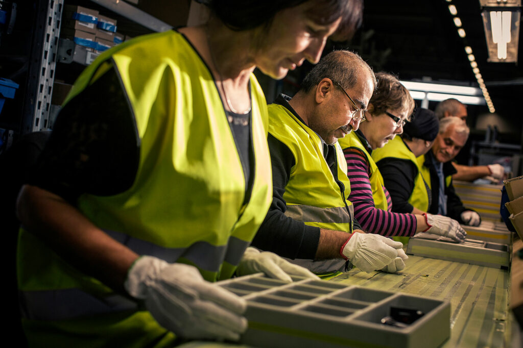 Flera personer som jobbar i en produktionskedja. De är koncentrerade på sitt arbete.