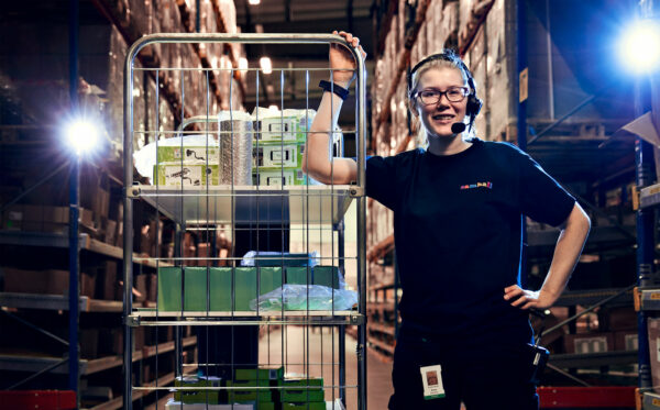 Kvinna håller i en lastvagn. Hon ler mot kameran.