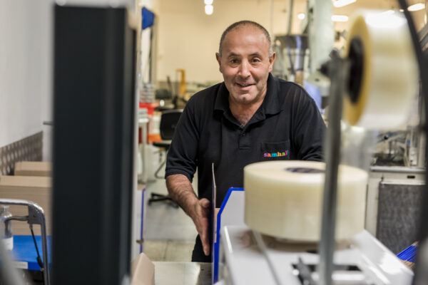 Carlos Diaz packar producter i lådor. Han bär svart klädsel. 