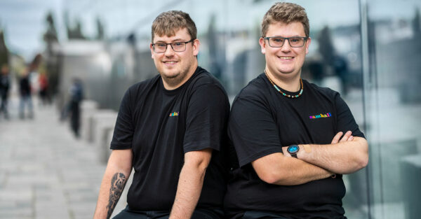 Tvillingar kollar in i kameran. De har brunt hår och glasögon samt Samhall-tröja