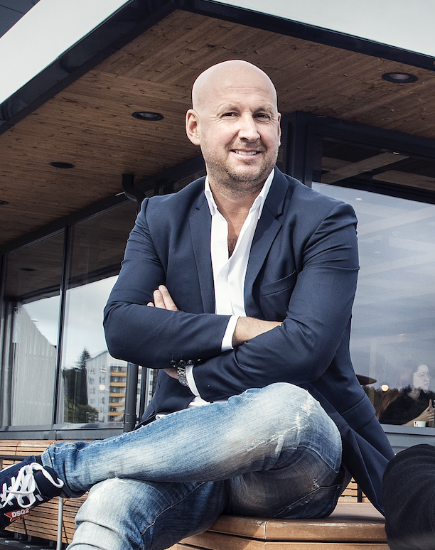 Bild på Christoffer Bergfors som sitter med armarna i kors framför en Max-restaurang.