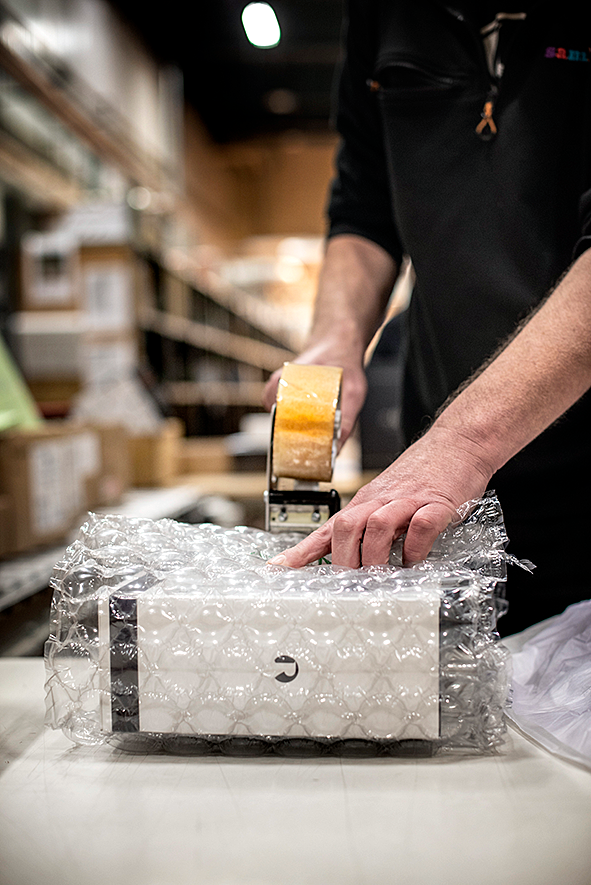 Man ser en persons händer tejpa ihop ett paket