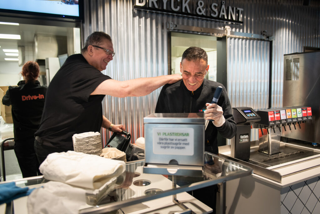 Humberto Rengifo står tillsammans med sin kollega bakom disken på restaurangen. De skrattar båda två.