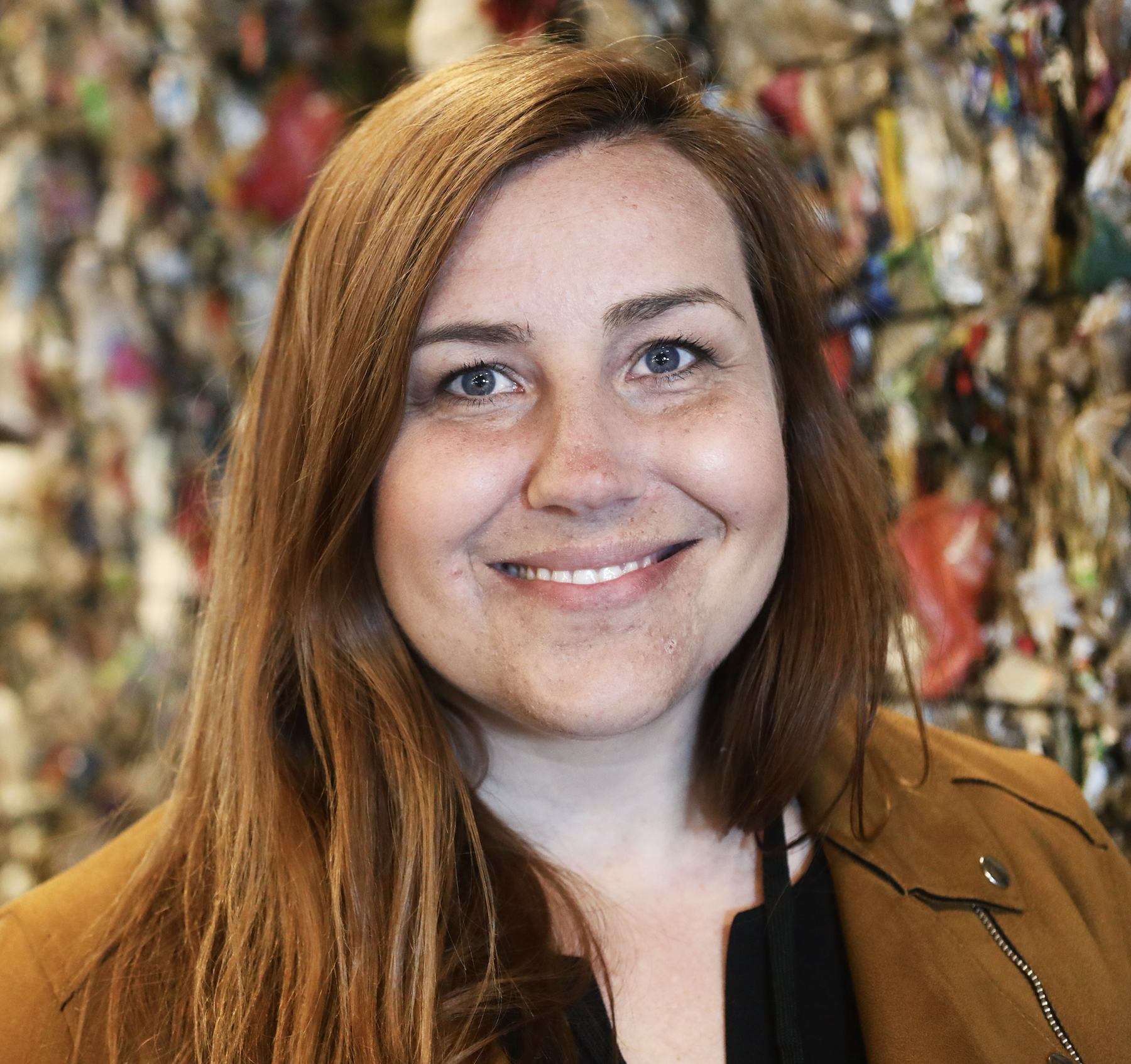 Porträttbild på Sara William som är områdeschef på Samhall. I bakgrunden syns plastskräp från lokalen.