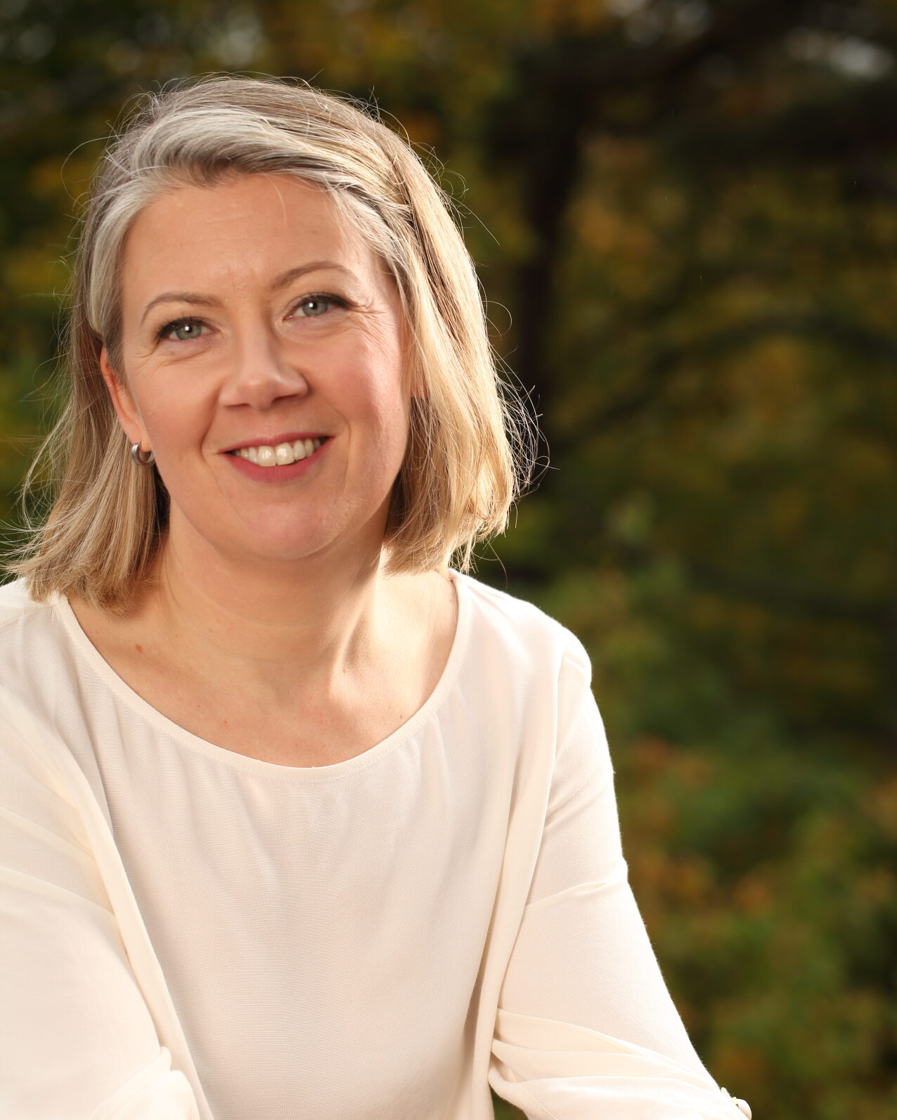Porträtt av Julia Klingspor med vit tröja, axellångt ljust hår och blågrå ögon.