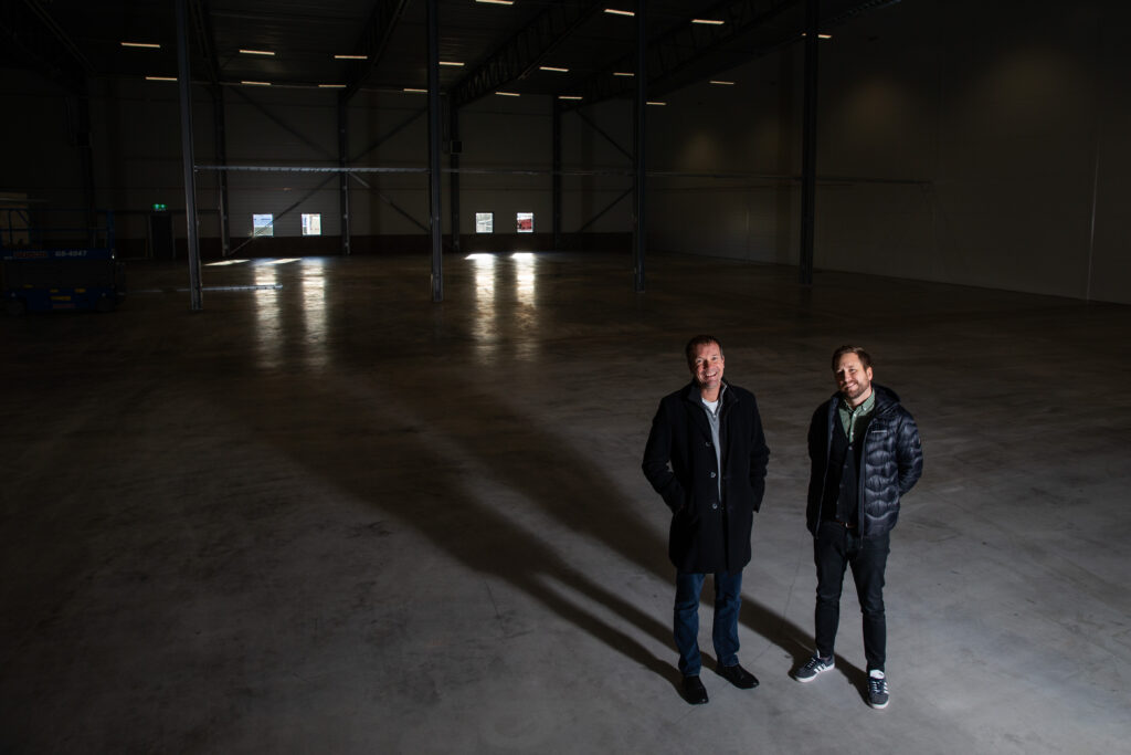 Två personer i nedsläckt lokal. Tittar in i kameran från ett fågelperspektiv.