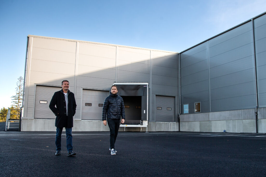 Två män promenerar utomhus utanför lokalen.