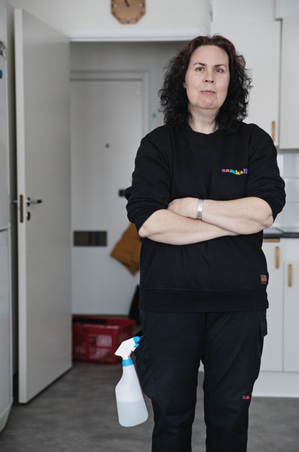 Porträttbild på Monica Nilsson. Hon har långt svart hår och bär svart Samhall-uniform.