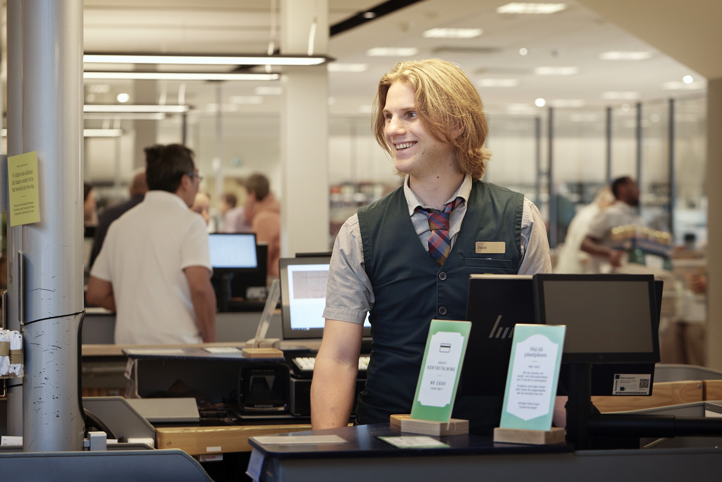 Bild på Johan som sitter i kassan i Systembolagets butik.