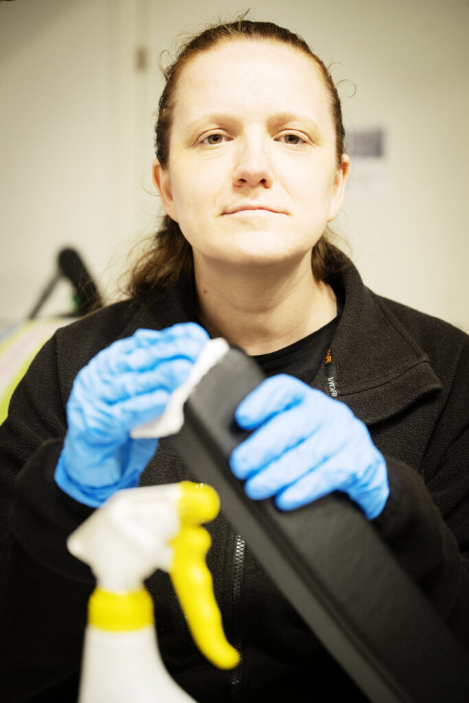 bild på en kvinna som putsar på ett armstöd till en rullstol.