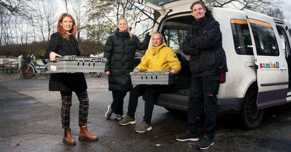 Bild på fyra personer utomhus som står vi en it bil.