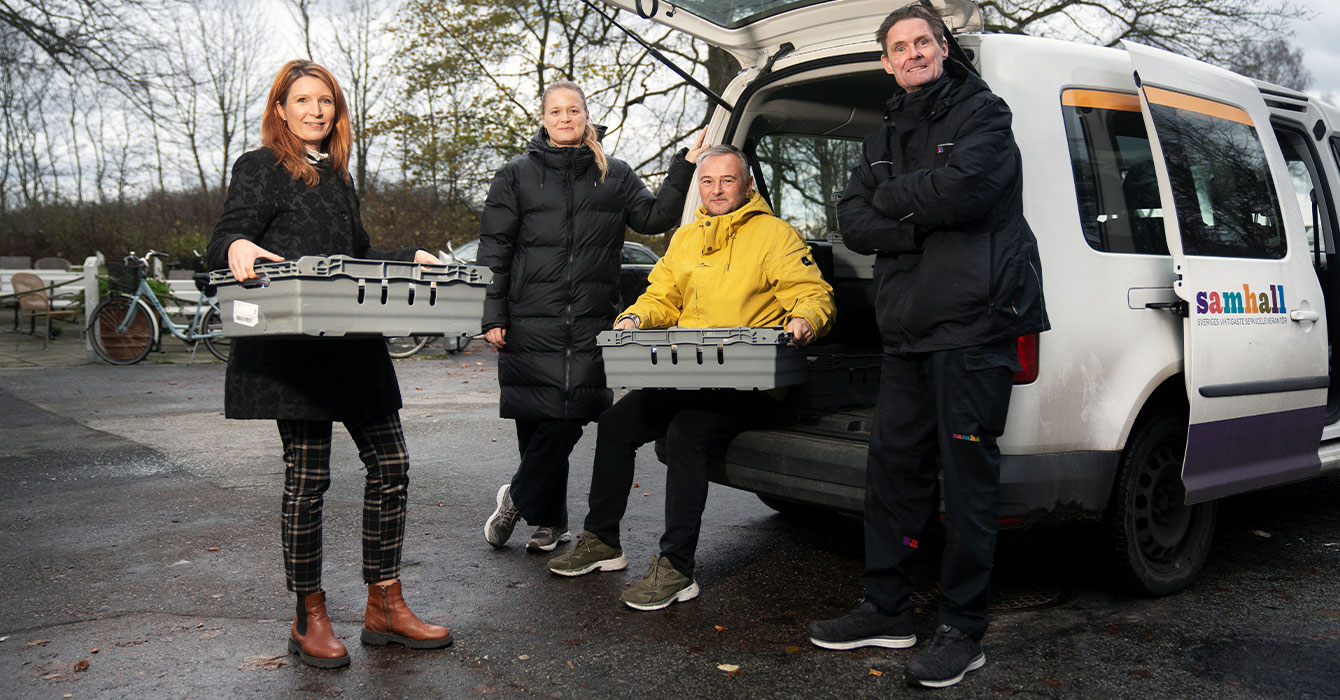 Bild på fyra personer utomhus som står vi en it bil.