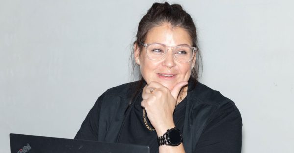 Bild p åen kvinna osm ler och håller sin vänstra hand lutat mot hakan.